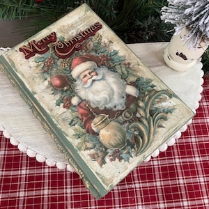 May include: A vintage-style Christmas-themed book with a Santa Claus illustration on the cover. The cover features the words "Merry Christmas" in a decorative font. The book has a distressed, aged appearance with green edges.