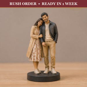 May include: A custom 3D figurine of a couple standing together on a circular base. The person on the left wears a tan trench coat over a floral dress and white sneakers. The person on the right wears a dark jacket, beige shirt, tan pants, and white sneakers.