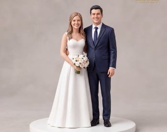 Könnte beinhalten: Eine Hochzeitstortenfigur, die ein Paar zeigt, das nebeneinander auf einem runden Sockel steht. Die linke Figur trägt ein weißes ärmelloses Kleid und hält einen Strauß aus rosa und weißen Rosen. Die rechte Figur trägt einen marineblauen Anzug.