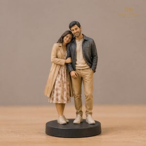 May include: A miniature figurine of two people standing together on a circular black base. One person wears a long beige coat over a floral dress and white sneakers. The other person wears a dark gray jacket over a beige shirt, tan pants, and white sneakers.