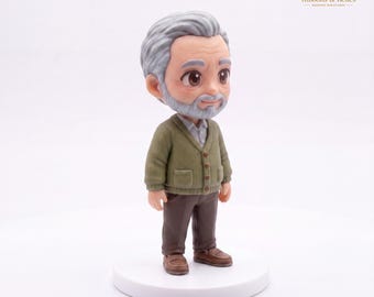 May include: A miniature figurine of an older person with gray hair and a beard, wearing a light green button-up cardigan over a white collared shirt, brown trousers, and brown shoes, standing on a circular white base against a plain background.