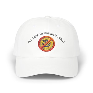 May include: White baseball cap featuring the text "I'll take my whiskey...neat" and a circular graphic with a crossed-out eagle and the words "Immigration Customs Enforcement".
