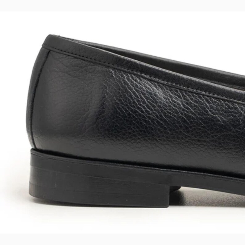 Handmade black full grain leather tassel loafers for men with moc toe stitching, slip-on design, and durable rubber outsole on a white background.