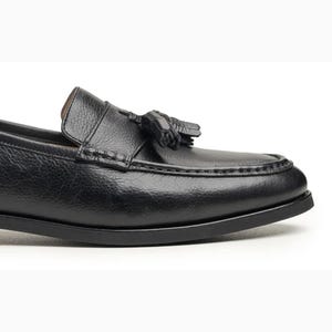 Handmade black full grain leather tassel loafers for men with moc toe stitching, slip-on design, and durable rubber outsole on a white background.