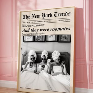 Puede incluir: Una impresión en blanco y negro enmarcada con un diseño de periódico, titulada "The New York Trends". La imagen muestra a tres personas con toallas y gafas de sol, usando teléfonos. El texto dice "And they were roommates."