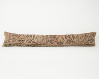 May include: A long, rectangular pillow with a faded, vintage look. The pillow features a detailed, patterned design in shades of beige, brown, and green. The pillow is likely used for decorative purposes.