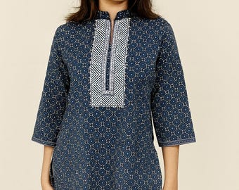 May include: A navy blue tunic top with a geometric pattern and a white embroidered panel down the front. The top has three-quarter sleeves and is paired with white pants. The tunic is a casual, everyday garment.