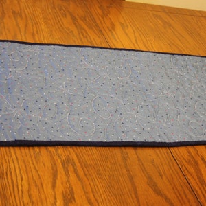 Puede incluir: Un camino de mesa acolchado azul con un patr&oacute;n de lunares blancos y rojos y un borde azul marino.