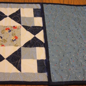 Puede incluir: Un camino de mesa acolchado azul y blanco con un patr&oacute;n floral en el centro y un patr&oacute;n de lunares azul y blanco en los lados.