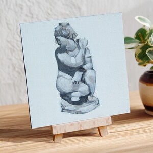 May include: A grayscale painting of a classical sculpture on a small canvas. The artwork depicts a seated figure with a detailed head and draped clothing. The canvas is displayed on a wooden easel, with a plant in a decorative pot in the background.