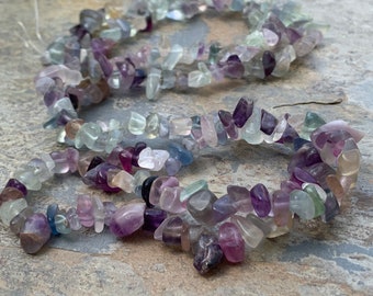 May include: A strand of multi-colored fluorite chip beads. The beads are a mix of purple, green, and blue.