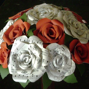 May include: A bouquet of paper roses made from sheet music. The roses are a mix of white and red.