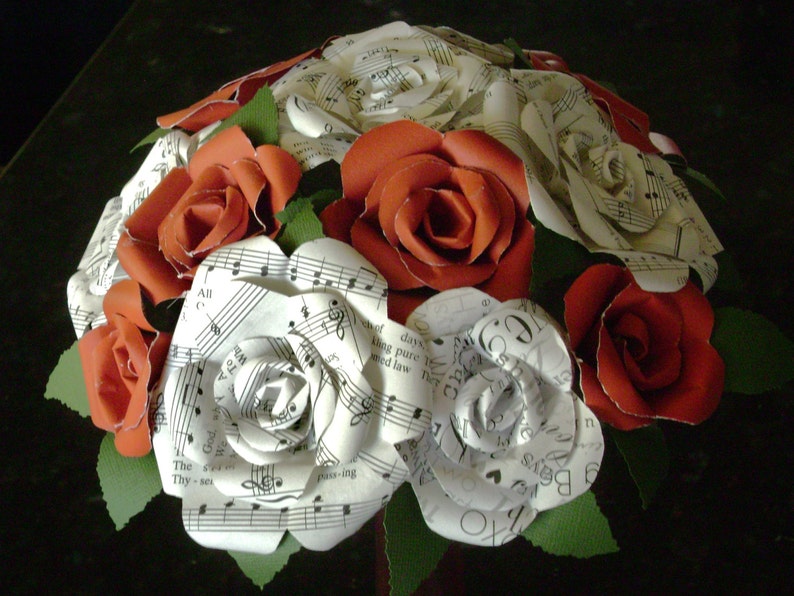 May include: A bouquet of paper roses made from sheet music. The roses are a mix of white and red.