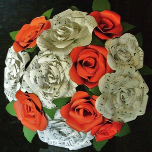 May include: A bouquet of paper roses made from sheet music. The roses are a mix of white and red.