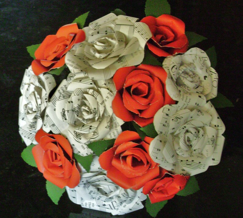 May include: A bouquet of paper roses made from sheet music. The roses are a mix of white and red.