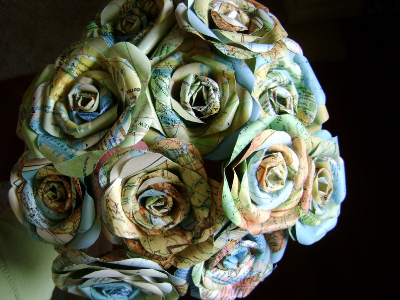 May include: A bouquet of paper roses made from maps in shades of blue, green, and brown. The roses are arranged in a circular shape, with the stems hidden from view.