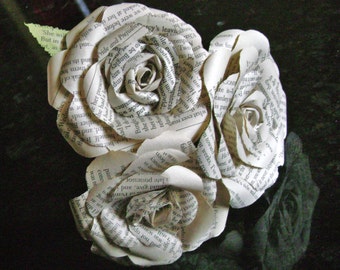 May include: Three white paper roses made from pages of a book. The roses are arranged in a bouquet and have a vintage aesthetic.