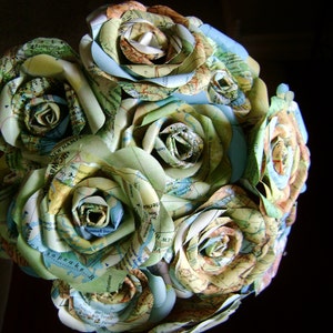 May include: A bouquet of paper roses made from maps, featuring shades of green, blue, and beige. The roses are arranged in a circular shape, creating a unique and artistic floral arrangement.