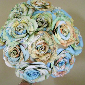 May include: A bouquet of paper roses made from maps in shades of blue, green, and brown. The roses are arranged in a circular shape and are tied together with a ribbon.