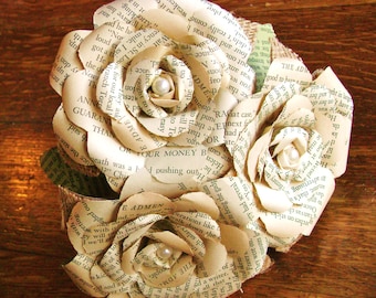 Puede incluir: Tres rosas de papel hechas con páginas viejas de libros, con detalles de arpillera y adornos de perlas. Las rosas están dispuestas en un racimo, con los tallos hacia abajo.
