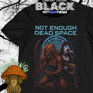 May include: Black t-shirt with the text "NOT ENOUGH DEAD SPACE" in light blue. The graphic features two figures, one with red skin and long hair, and the other with pale skin and dark hair, holding a microphone. The shirt has the words "COMFORT COLORS" and "SOFT FADED VINTAGE".