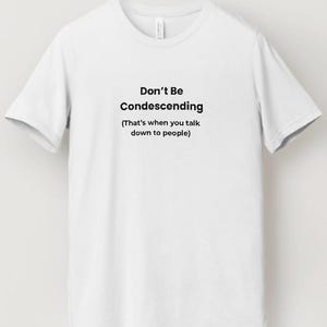 May include: A white t-shirt with the text "Don't Be Condescending" in black, with the phrase "(That's when you talk down to people)" below it. The shirt has short sleeves and a crew neck.