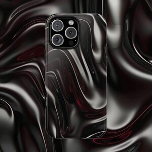 May include: A black and red swirled phone case with a glossy finish. The case has a camera module with four lenses. The background features a similar swirled pattern.