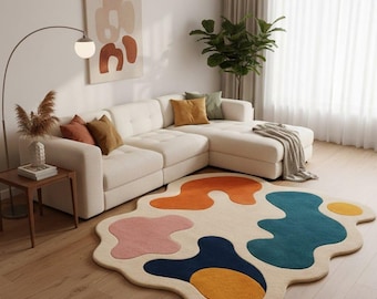Könnte beinhalten: Ein modernes Wohnzimmer mit einem cremefarbenen Ecksofa, einem farbenfrohen abstrakten Teppich und einer Stehlampe. Der Teppich hat eine einzigartige Form mit orangefarbenen, blauen, rosa und gelben Formen. Dekorative Kissen in verschiedenen Farben tragen zur Ästhetik des Raumes bei.