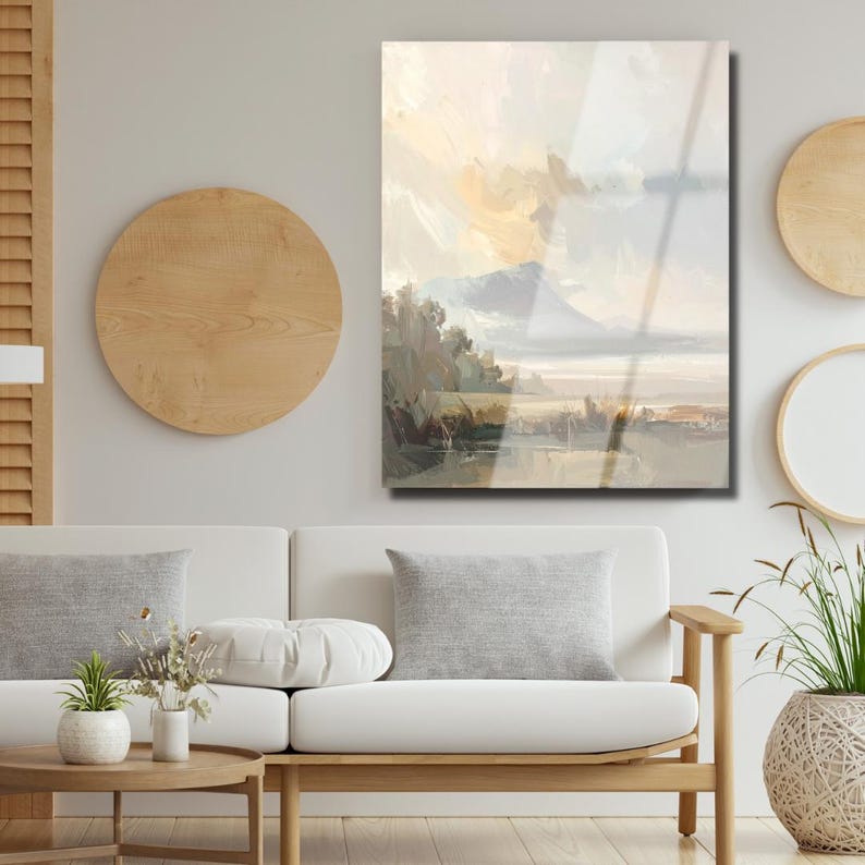 Peut inclure: Peinture de paysage avec une cha&icirc;ne de montagnes, des arbres et un plan d'eau. L'&oelig;uvre pr&eacute;sente des couleurs douces et sourdes, notamment beige, gris et des touches de jaune. Accroch&eacute;e au-dessus d'un canap&eacute; blanc.
