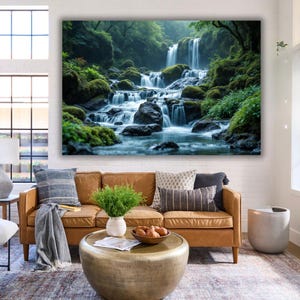 May include: A large canvas print depicting a waterfall in a verdant forest. The water cascades over mossy rocks, creating a tranquil scene. The print is displayed above a brown leather sofa in a living room setting, with a coffee table in front.