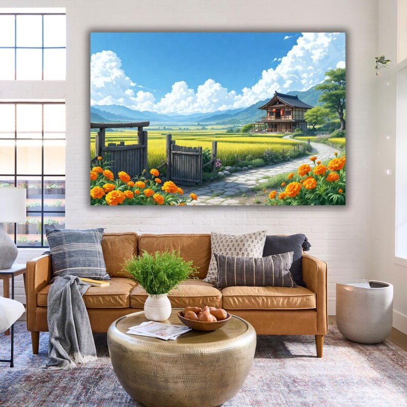 May include: A large canvas print depicts a serene Japanese landscape. A traditional house sits near a path, surrounded by golden fields and orange flowers. The sky is blue with fluffy white clouds. The print is displayed above a brown leather sofa.