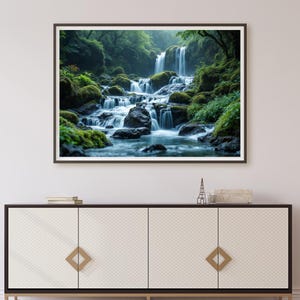May include: A framed print of a waterfall scene. The image depicts a vibrant green forest with a waterfall cascading over rocks. The water flows through the scene, creating a sense of peace and natural beauty. The print is framed in a dark wooden frame.