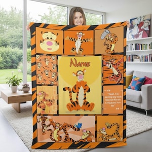 Puede incluir: Una manta grande naranja y negra con múltiples imágenes del personaje de dibujos animados Tigger. La manta tiene una imagen central con el nombre "Name" encima de Tigger. La manta tiene una burbuja de cita con texto.