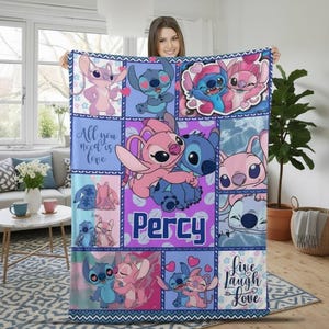 Könnte beinhalten: Eine bunte Decke mit Cartoon-Figuren in Blau und Rosa. Das Design enthält den Text "All you need is love" und "Live Laugh Love". Der Name "Percy" wird auf einem lila Hintergrund angezeigt. Blaue Bordüre.