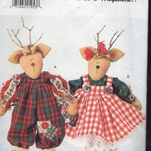 May include: A Butterick pattern for two reindeer dolls. One doll wears red and green plaid overalls, the other a red and white checkered dress. Both have twig antlers, tan ears, and are labeled "A" and "B". The text "Needle in a Haystack!!" is visible.