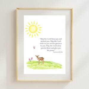 May include: A framed watercolor print featuring a yellow sun, a deer, and the text "May the Lord bless you and protect you..." from Numbers 6:24-26. The artwork includes a butterfly and pink flowers on a green hill.