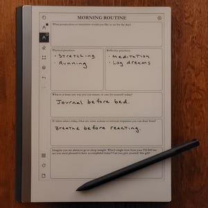 Könnte beinhalten: Ein digitales Notizbuch mit einem schwarzen Stift auf einer Holzoberfläche. Das Notizbuch zeigt eine Vorlage für die "MORNING ROUTINE" mit handschriftlichen Notizen, darunter "Stretching", "Running", "Meditation" und "Log dreams".