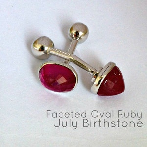 May include: A pair of silver cufflinks with faceted oval ruby gemstones. The cufflinks are a July birthstone.