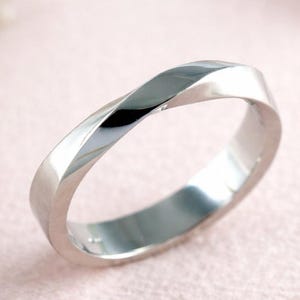 Aliança de casamento em ouro 14k com design moderno e minimalista, em formato de Möbius, com 4 mm de largura.