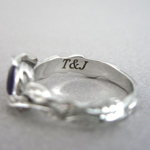 May include: Silver ring with a purple gemstone and an inscription on the inside band that reads "T&J".