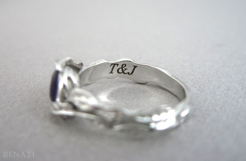 May include: Silver ring with a purple gemstone and an inscription on the inside band that reads "T&J".