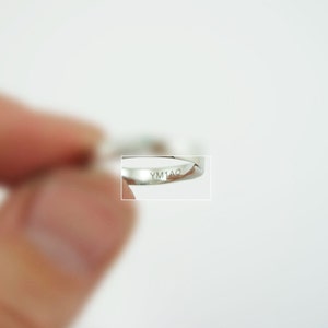 May include: Close-up of a silver ring with the inscription "YM1AO" on the inside band.