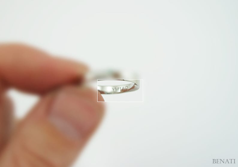May include: Close-up of a silver ring with the inscription "YM1AO" on the inside band.