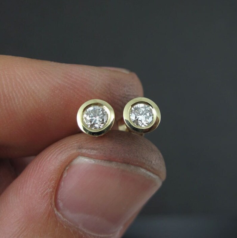May include: A pair of gold stud earrings with round, clear gemstones.