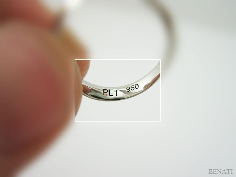 May include: Close-up of the inside of a silver ring with the inscription "PLT 950" engraved on the band.