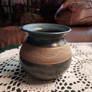 May include: A blue and brown ceramic vase with a textured design. The vase is round and has a wide opening.
