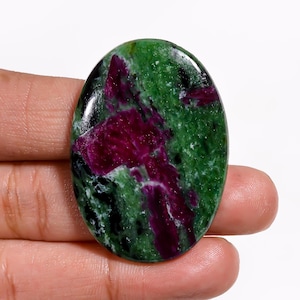May include: Oval-shaped ruby zoisite gemstone. The polished stone features a vibrant mix of colours, with deep magenta ruby inclusions set against a green zoisite background. The stone is smooth and glossy.