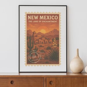 Może przedstawiać: Oprawiony wydruk artystyczny Nowego Meksyku. Wydruk przedstawia wzór znaczka pocztowego w stylu vintage z pustynnym krajobrazem, w tym kaktusy, budynki i zachód słońca. Tekst brzmi "New Mexico The Land of Enchantment".