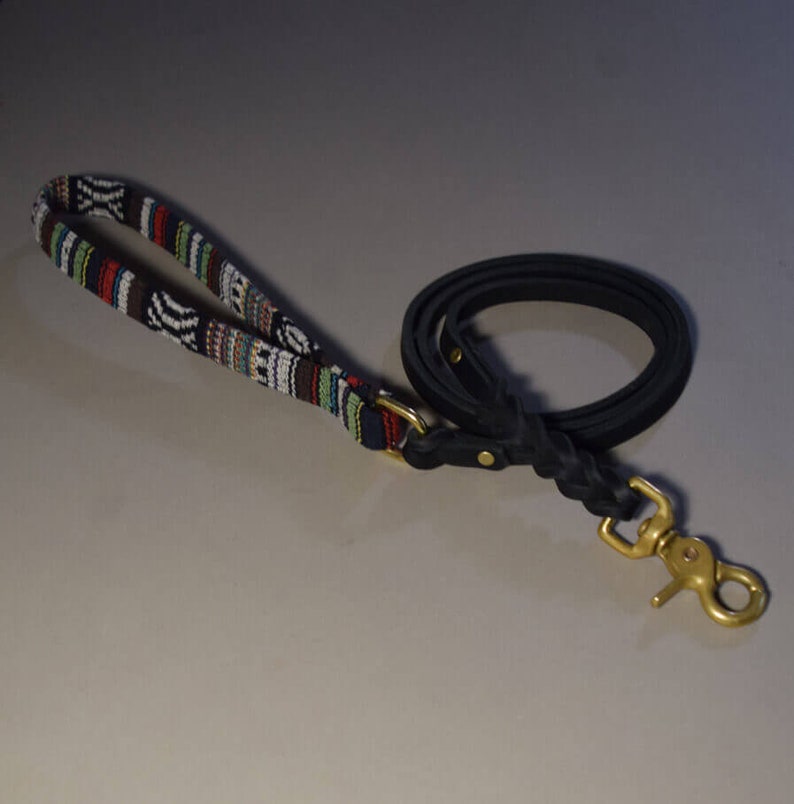 May include: A black leather dog leash with a colorful woven handle and a brass clasp.