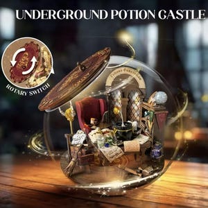 May include: A miniature Underground Potion Castle diorama inside a glass sphere. The scene includes a red armchair, a desk with potion bottles, and a cauldron. The diorama has a wooden door and a rotary switch. The text "Underground Potion Castle" is at the top.